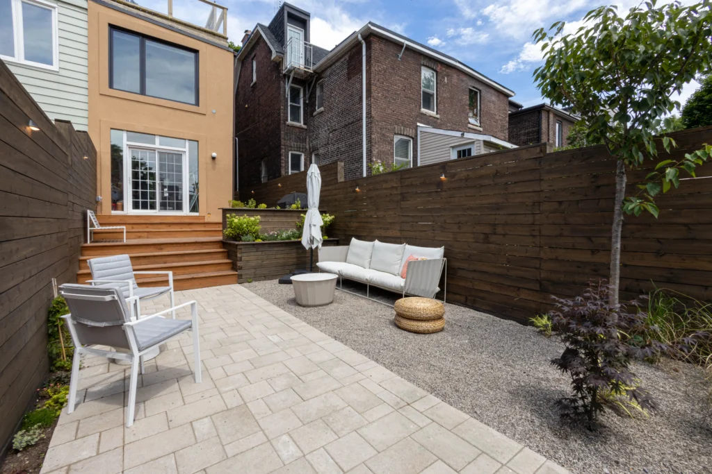 Multi-level backyard design with concrete steps, interlocking stone patio, cedar privacy fencing, and raised deck in Toronto