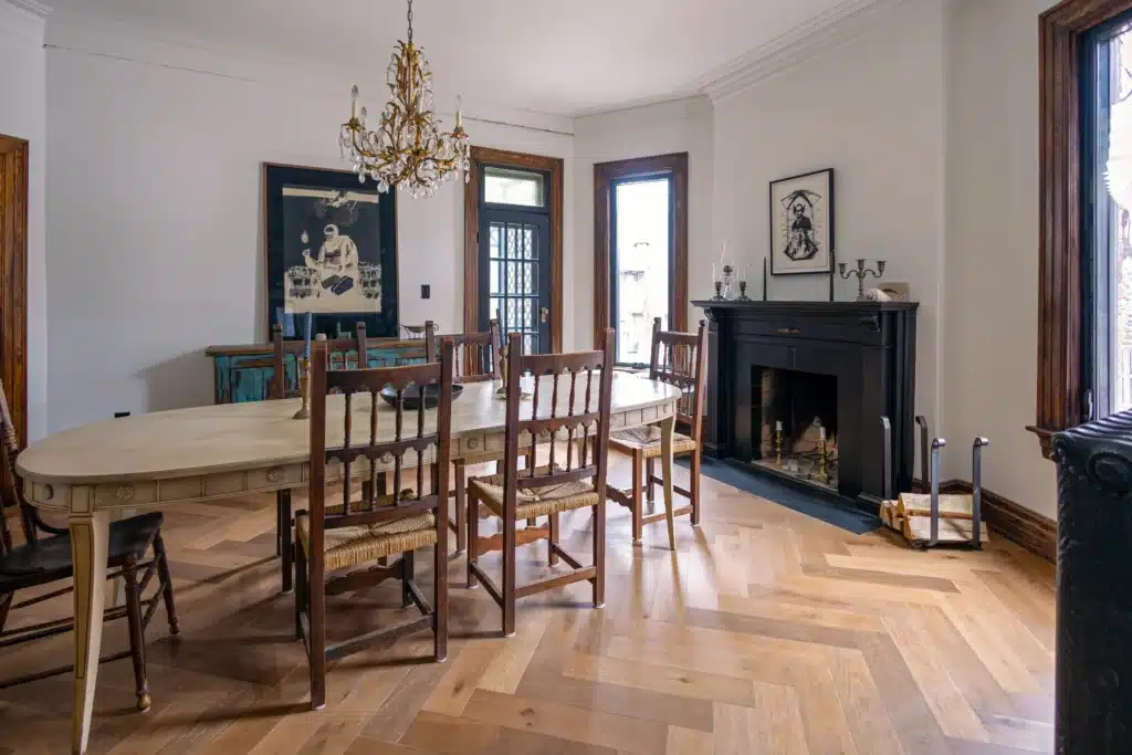 Victorian dining room renovation in Toronto with restored fireplace, wood herringbone flooring, and antique chandelier
