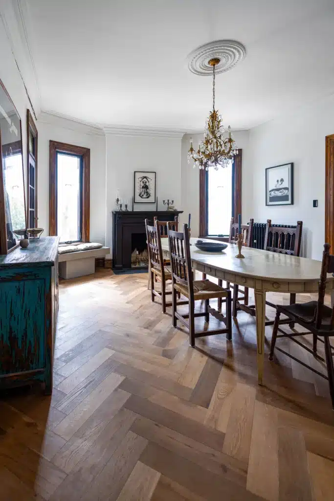 Victorian dining room renovation in Toronto with restored fireplace, wood herringbone flooring, and antique chandelier