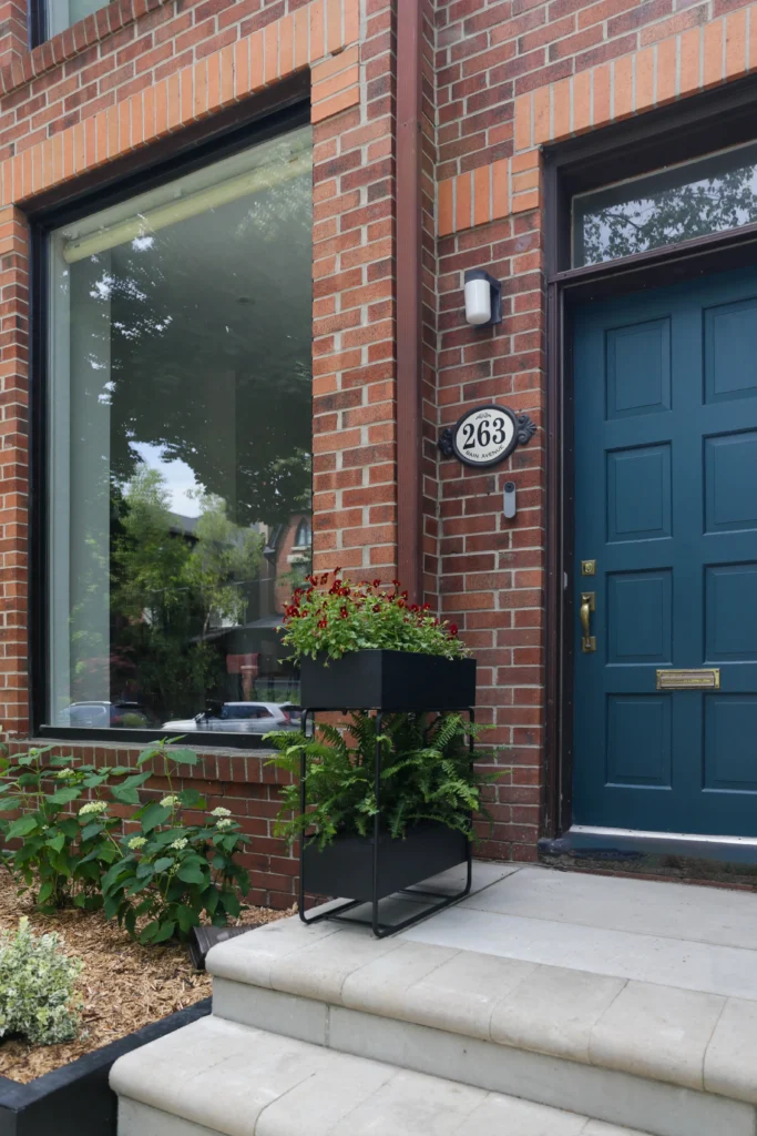 Front entrance landscaping detail with modern planter, stone steps, and soft garden planting in front of Toronto brick home