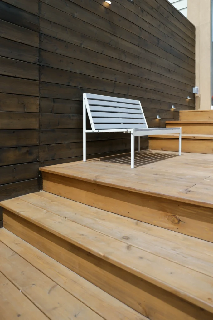 Multi-level backyard cedar deck with wide steps, modern privacy fencing, built-in planter, and patio stone base in Toronto