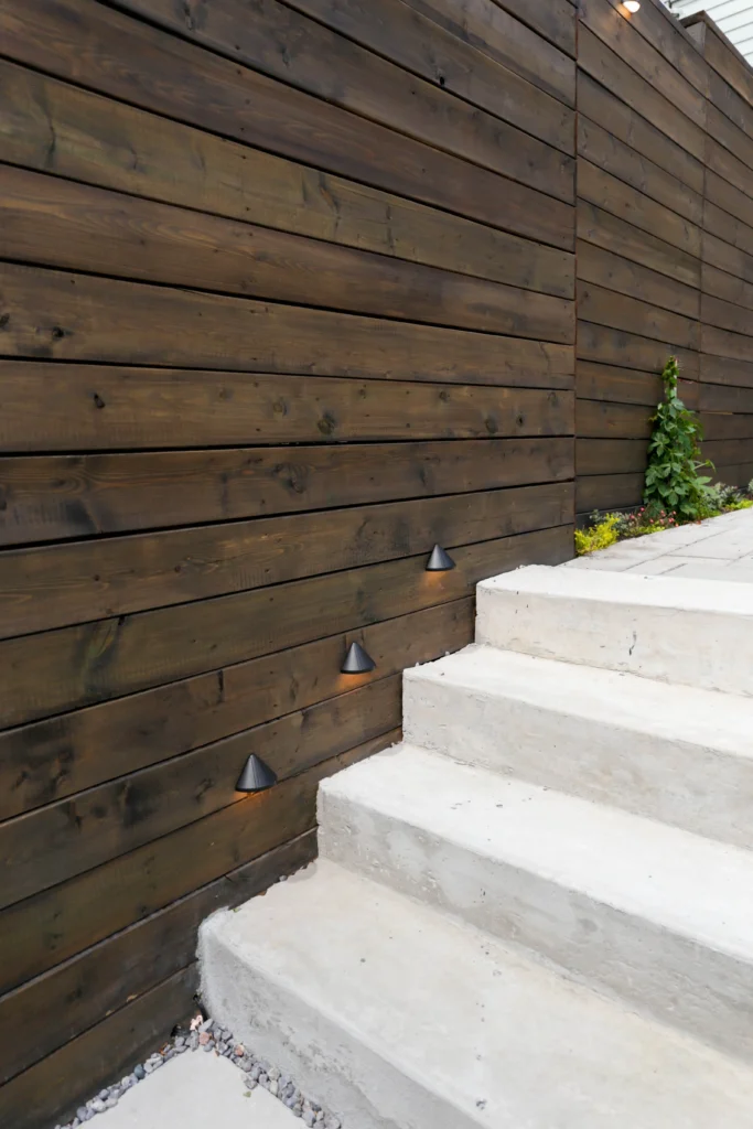 Concrete landscape steps with integrated step lighting, modern wood privacy fence, and clean hardscape detailing in Toronto