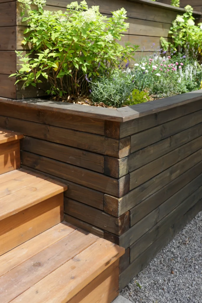 Backyard landscaping detail with gravel ground cover, ornamental trees, modern wood privacy fence, and integrated landscape lighting in Toronto