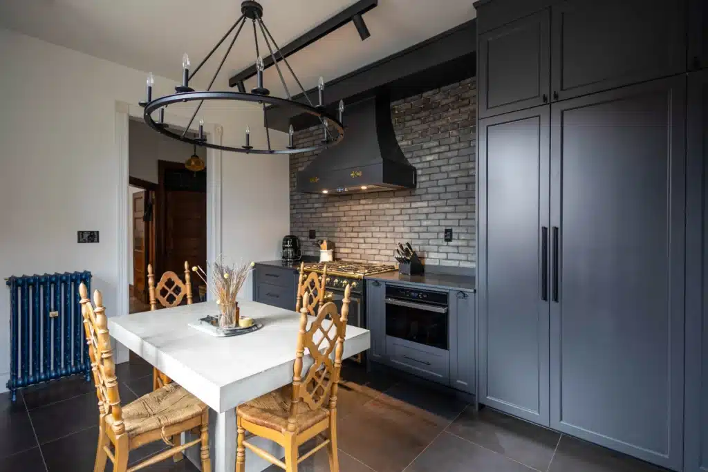 Victorian kitchen renovation in Toronto with dark custom cabinetry, farmhouse sink, and brass fixtures
