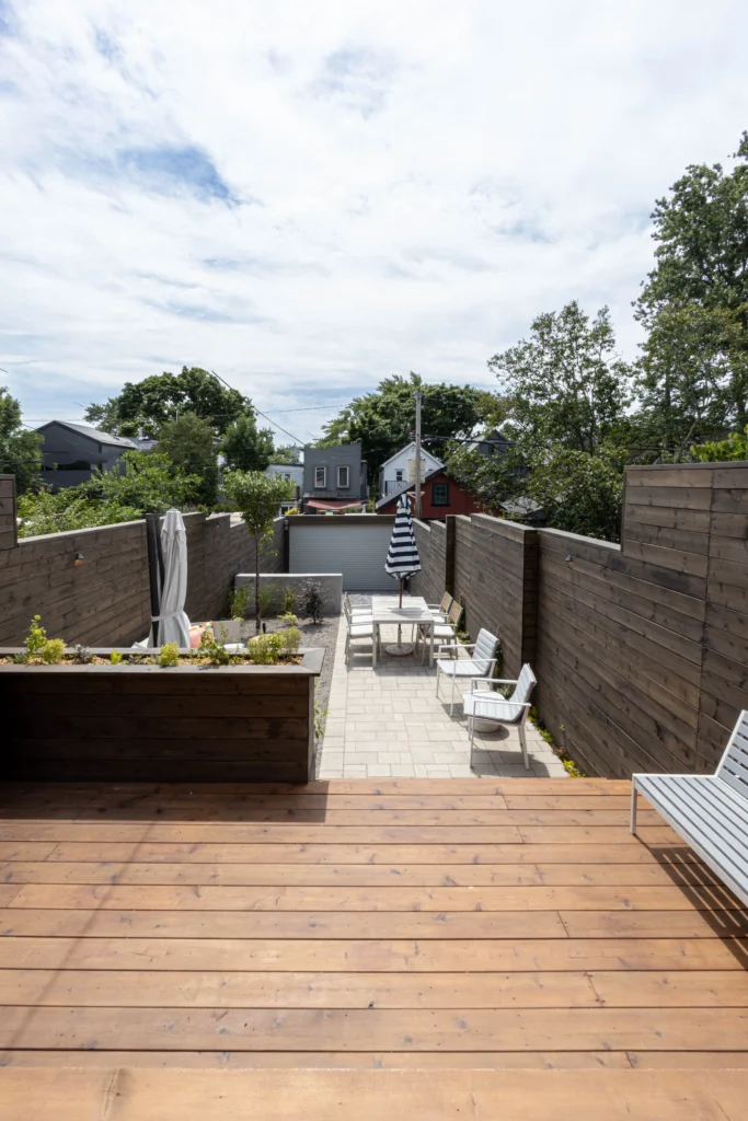 Multi-level backyard cedar deck with wide steps, modern privacy fencing, built-in planter, and patio stone base in Toronto
