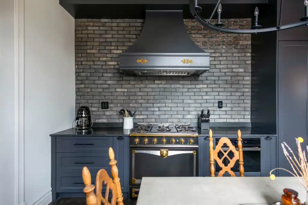 Victorian kitchen renovation in Toronto with dark custom cabinetry, farmhouse sink, and brass fixtures