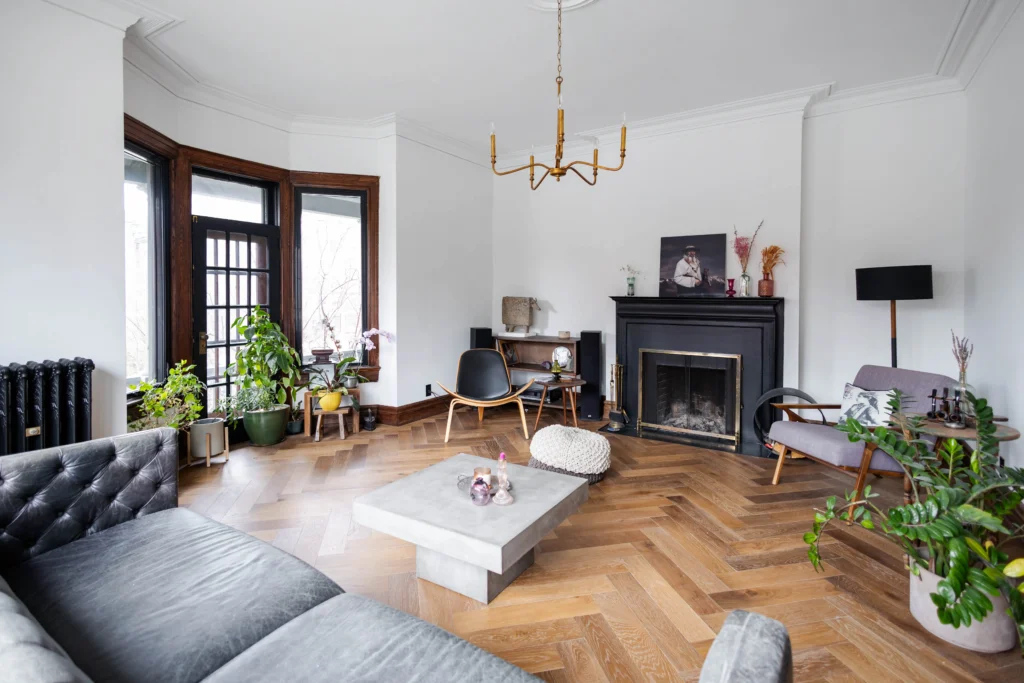 Victorian living room renovation in Toronto with large window, herringbone wood flooring, and restored original details