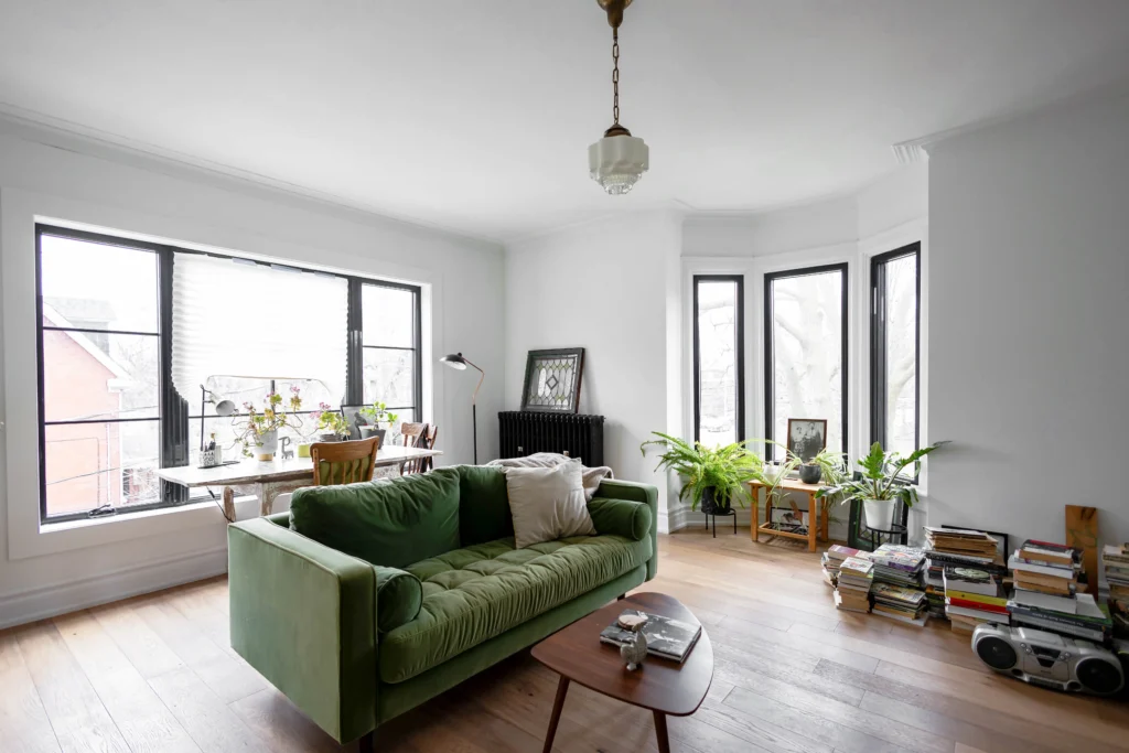 Victorian living room renovation in Toronto with large window, herringbone wood flooring, and restored original details