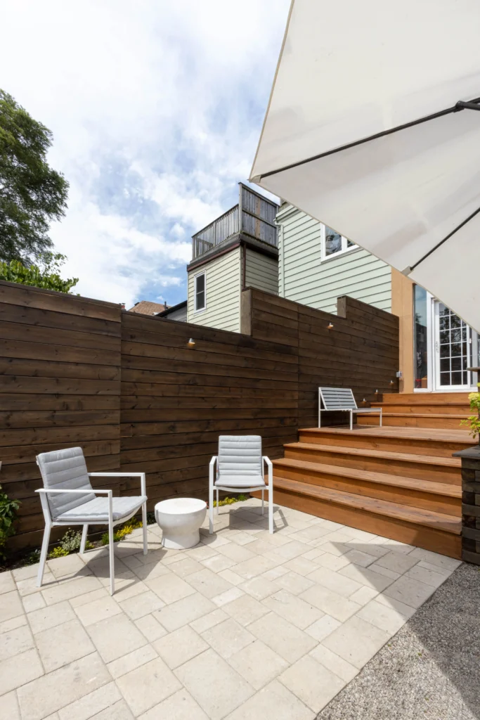 Multi-level backyard cedar deck with wide steps, modern privacy fencing, built-in planter, and patio stone base in Toronto