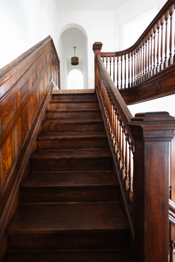 Restored Victorian staircase in Toronto home with original wood detailing, paneling, and herringbone flooring