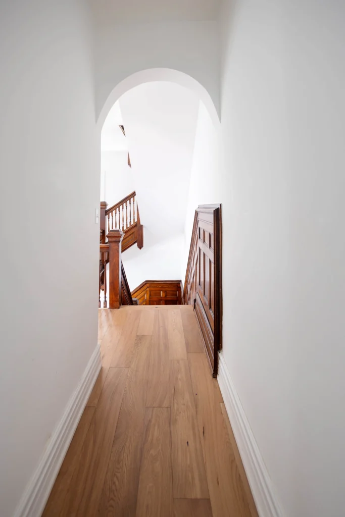 Restored Victorian staircase in Toronto home with original wood detailing, paneling, and herringbone flooring
