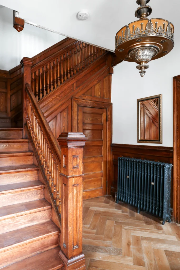 Restored Victorian staircase in Toronto home with original wood detailing, paneling, and herringbone flooring