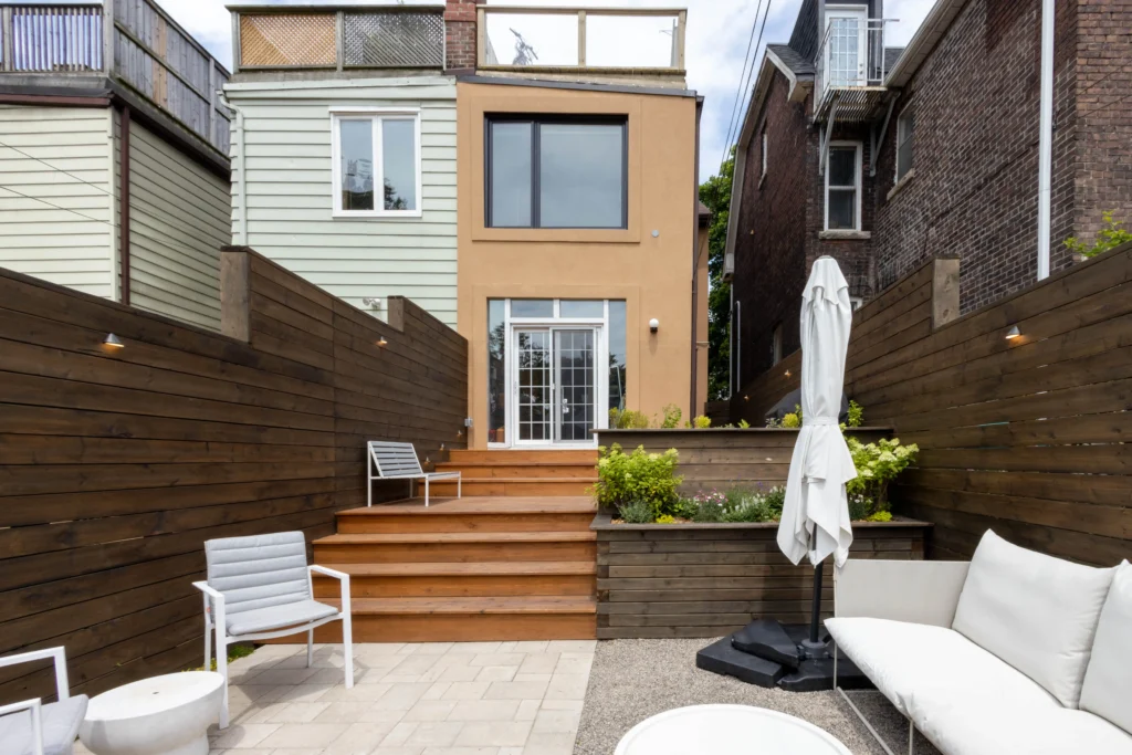 Modern backyard patio in Toronto with interlocking stone, gravel lounge area, cedar privacy fence, outdoor seating, and striped umbrella dining setup