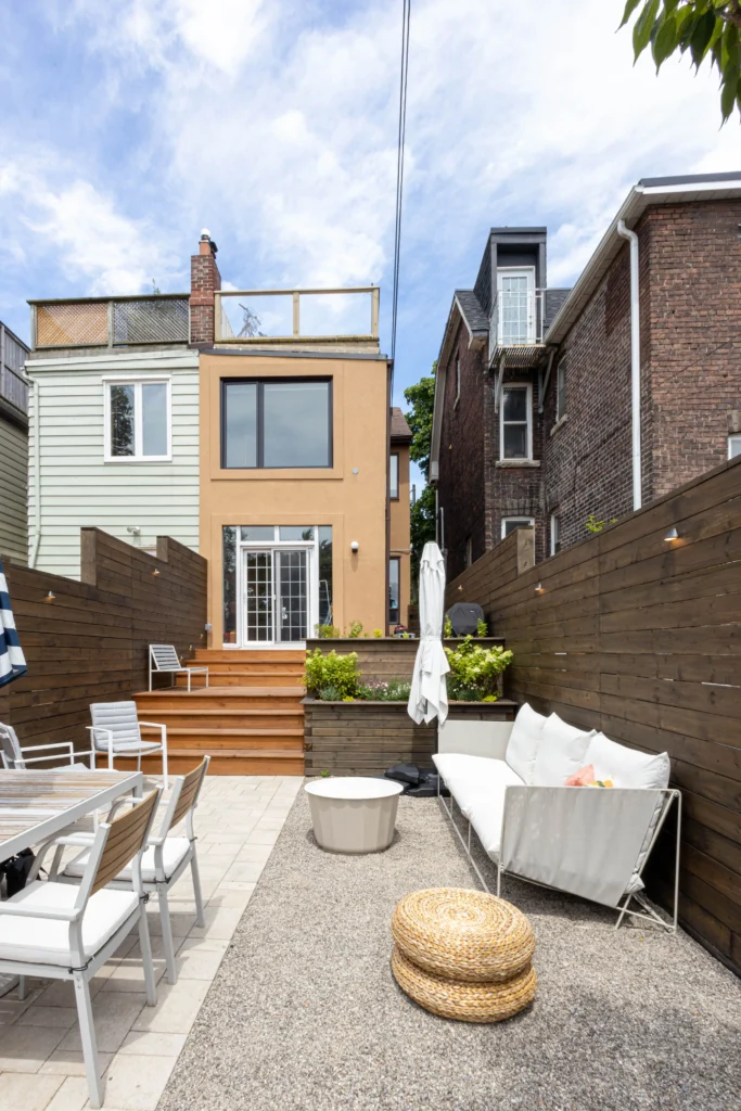 Modern backyard patio in Toronto with interlocking stone, gravel lounge area, cedar privacy fence, outdoor seating, and striped umbrella dining setup