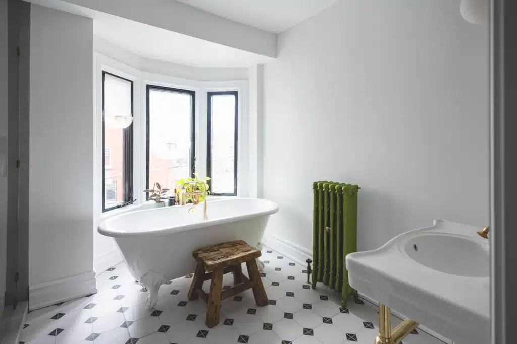 Modern bathroom renovation in Toronto Victorian home with glass shower, patterned tile floor, modern soakin tub with a green radiator