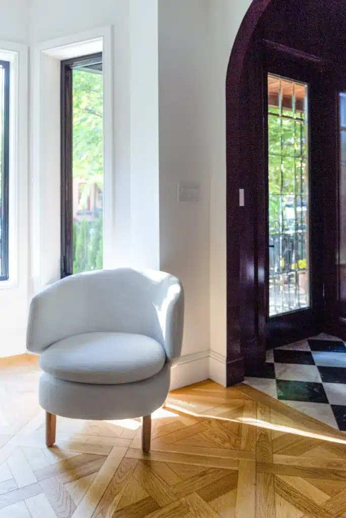Renovated home entryway with a deep burgundy arched alcove, black glass front door, black-and-white checkerboard floor, and light wood flooring.