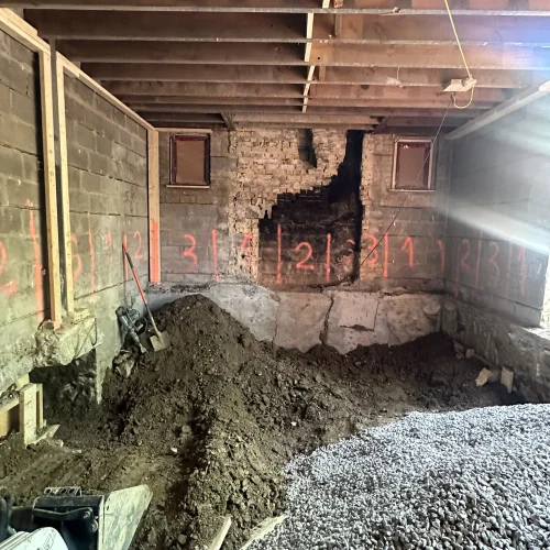 Basement underpinning in progress at a Toronto home — excavated floor, numbered foundation sections, and a Bobcat skid steer removing soil during a dig-down project by TMDC Group