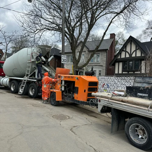 Concrete truck and pump equipment set up on a Toronto residential street during a basement underpinning project — TMDC Group crew preparing to pour foundation concrete at a GTA home