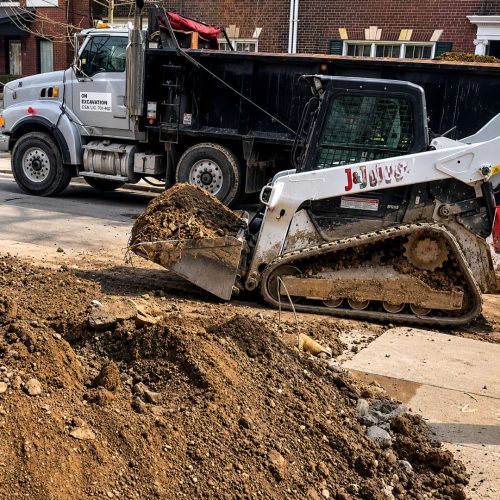 Compact excavator removing concrete debris during residential basement underpinning and excavation project in Toronto backyard construction site.